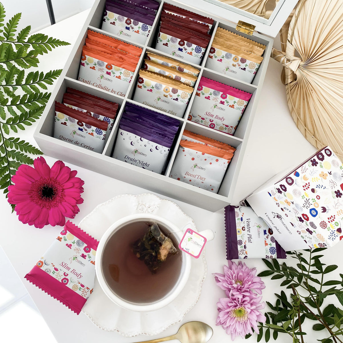 Sélection d’infusions FitClem en sachets autour d’une tasse de thé, dont Boost’Day et Drain’Night.